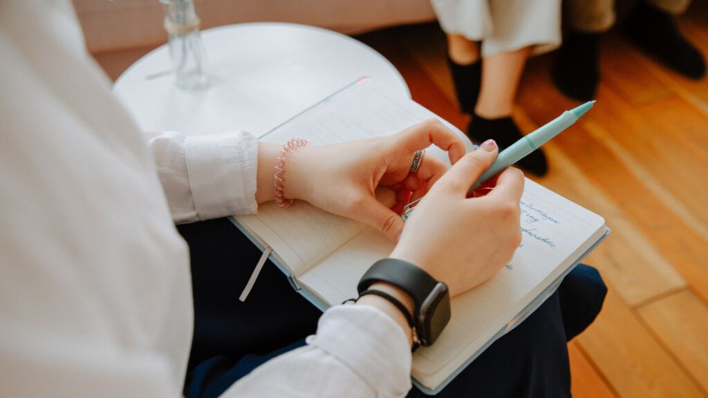 Nærfoto af hænder med notesbog og kugleben som billede på psykiater, der tager noter under udredning for autisme.