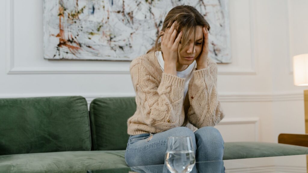 kvinde, der sidder i sofa og tager sig til hovedet som billede på nedsmeltning hos voksne med autisme